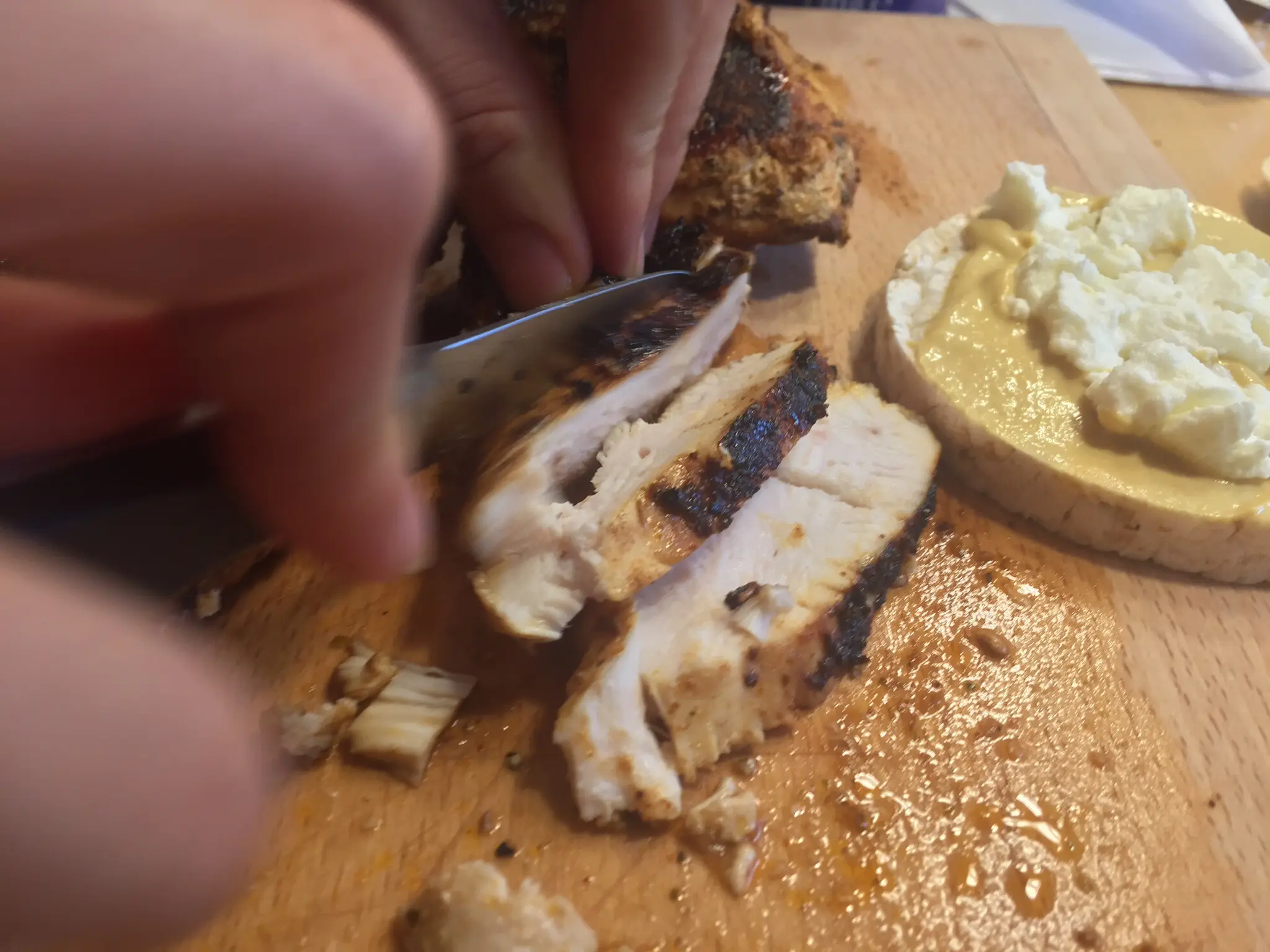 Slicing grilled chicken next to the topped rice cake