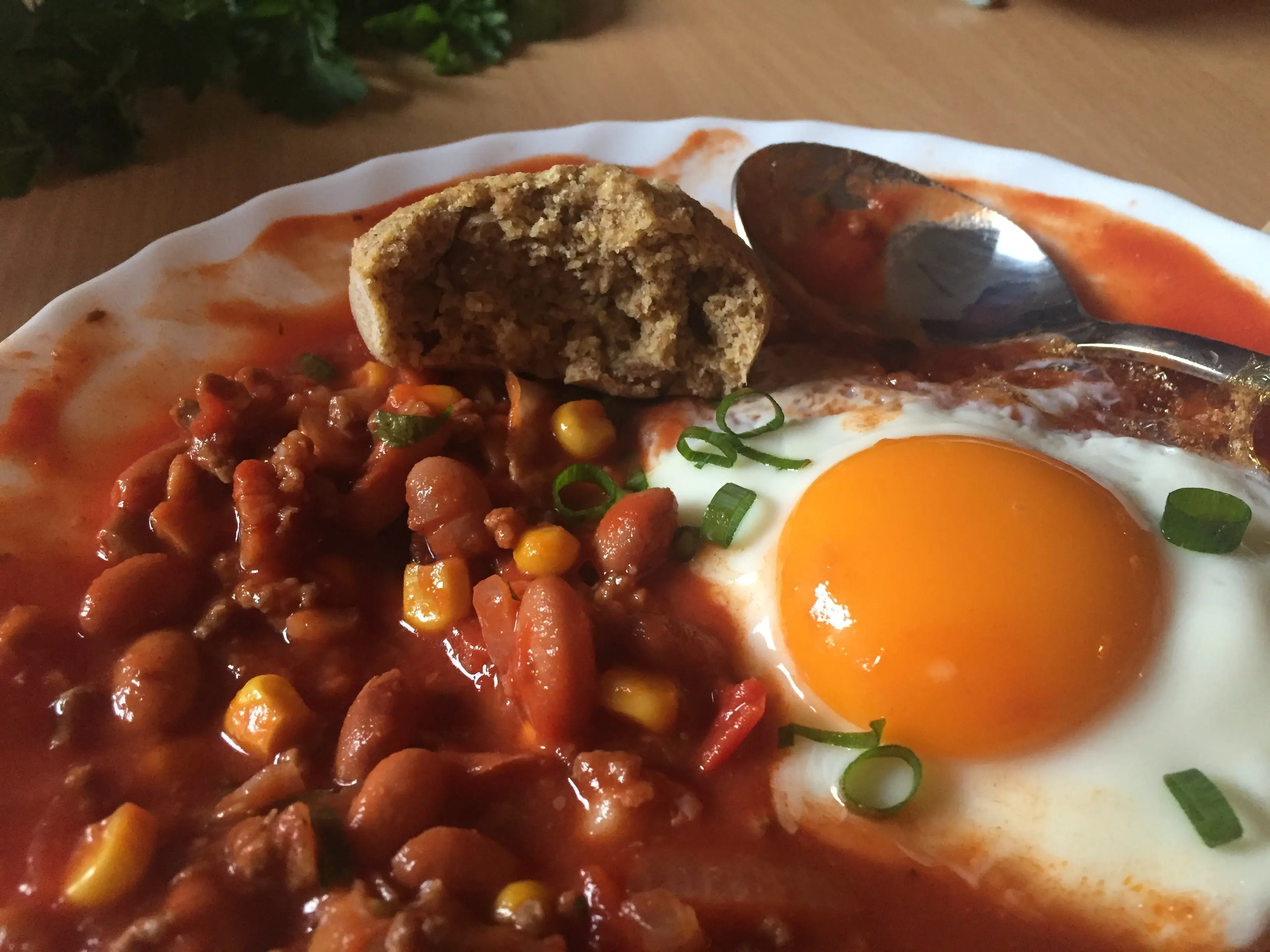 Homemade chili with an egg on top and cornbread.